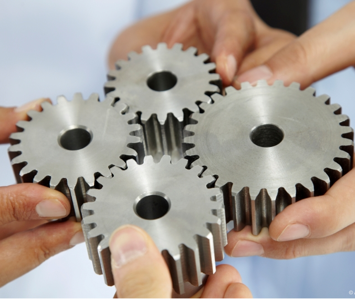 Hands holding four cog wheels together