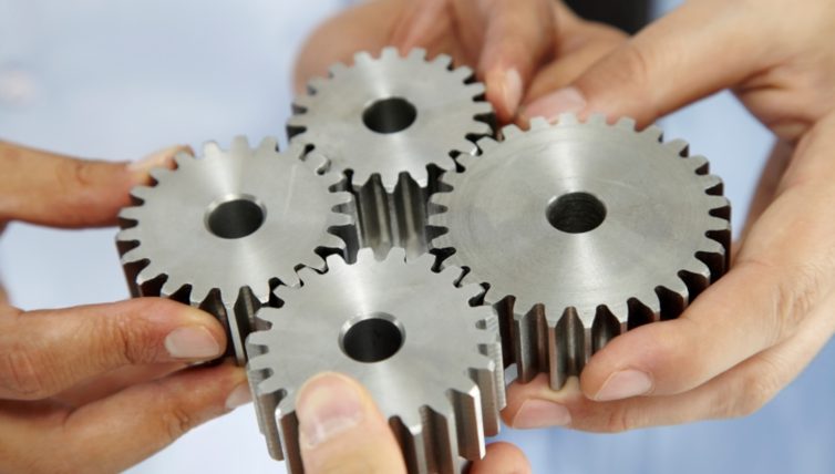 Hands holding four cog wheels together